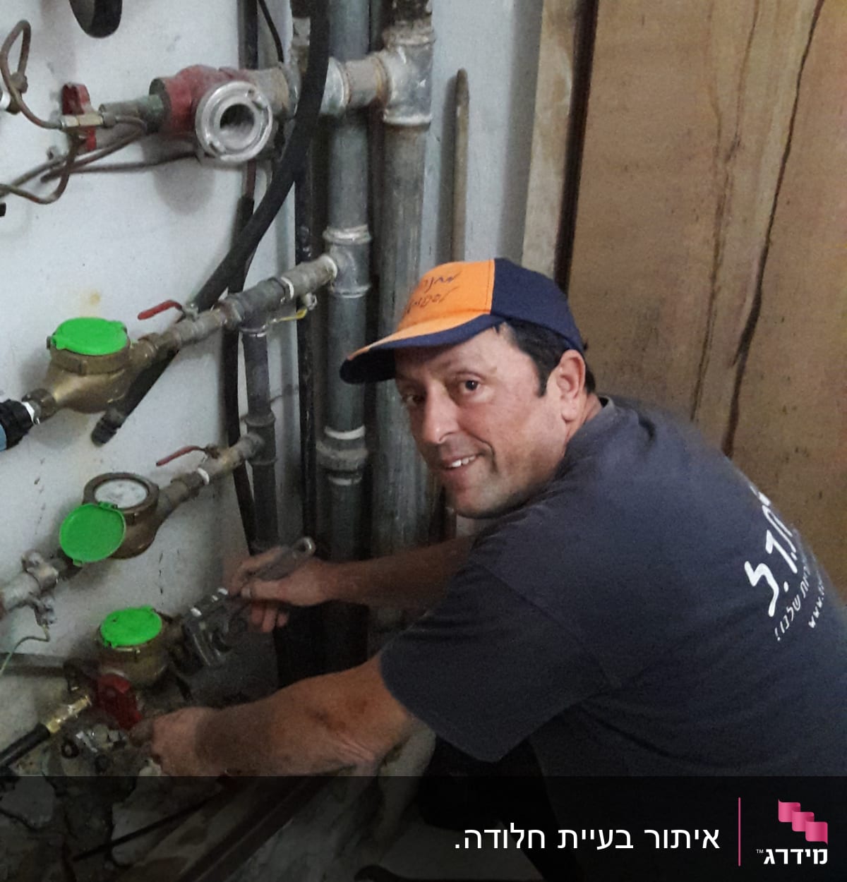 אדם עובד על צנרת עם מפתח צינורות